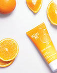 Top view of Yon-Ka Paris Creme Mains - Vitalite Sweet Orange (50 ml) with oranges in the background