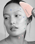 Diagram on face of model showing how to use the Odacite Crystal Contour Gua Sha Rose Quartz Beauty Tool (arrows showing direction of use and motion)