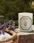 Lifestyle shot of Carriere Freres Lavender Candle (185 g) on stone wall with lavender bunch in the background