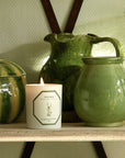 Lifestyle shot of Carriere Freres Ginger Candle (185 g) shown lit on shelf with green ceramic vases