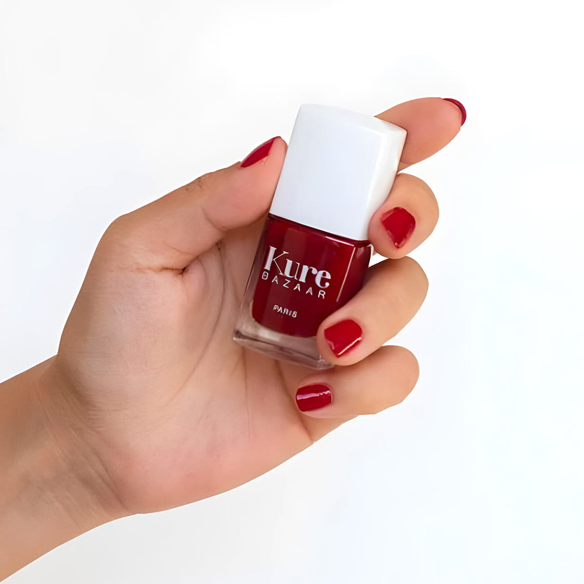 Close up of model wearing and holding bottle of Kure Bazaar Nail Lacquer - Sari (10 ml)