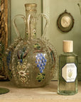 Lifestyle shot of Carriere Freres Lavender Room Spray (200 ml) with ornate painted vase in the background