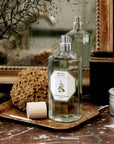Lifestyle shot of Carriere Freres Spearmint Room Spray (200 ml) with cap off on small wood tray on marble table and mirror in the background