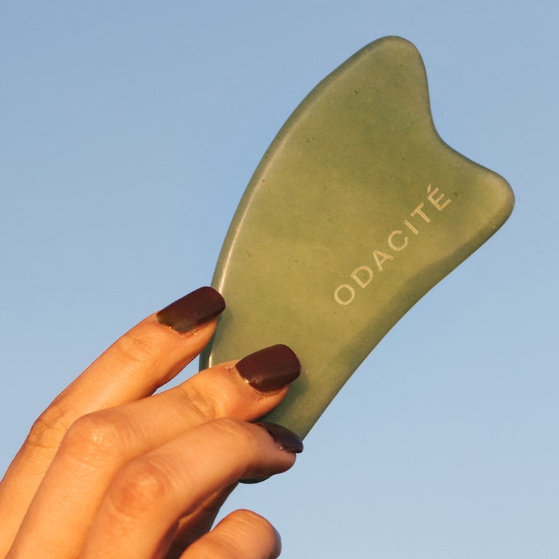 Close up of model holding Odacite Crystal Contour Gua Sha Green Adventurine Beauty Tool