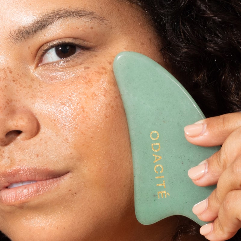 Close up of model using Odacite Crystal Contour Gua Sha Green Adventurine Beauty Tool on her face