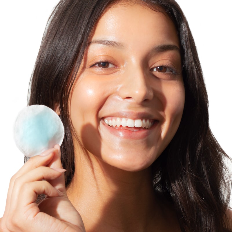 Close up of model holding a cotton pad with Odacite Blue Aura Cleansing Water on it