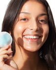 Close up of model holding a cotton pad with Odacite Blue Aura Cleansing Water on it