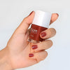Close up of model wearing and holding  bottle of Kure Bazaar Nail Lacquer - Blush (10 ml)