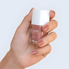 Close up of model wearing Kure Bazaar Nail Lacquer - Zoe (10 ml) and holding bottle