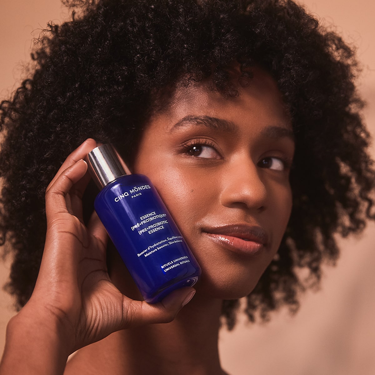 Model holding Cinq Mondes [Pre+Pro] Biotic Essence (100 ml) near face
