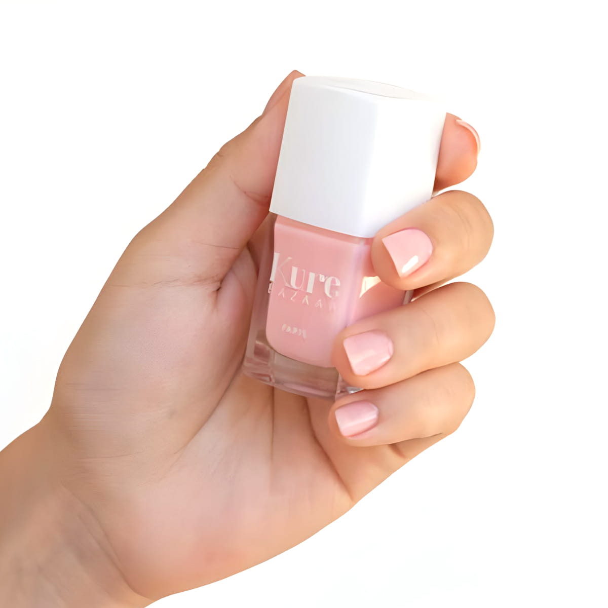 Close up of model wearing Kure Bazaar  Nail Lacquer - Rose Milk Glow and holding bottle (10 ml)