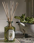 Lifestyle shot of Carriere Freres Orange Blossom Diffuser with reeds on decorative tile with strainer and vegetables in the background