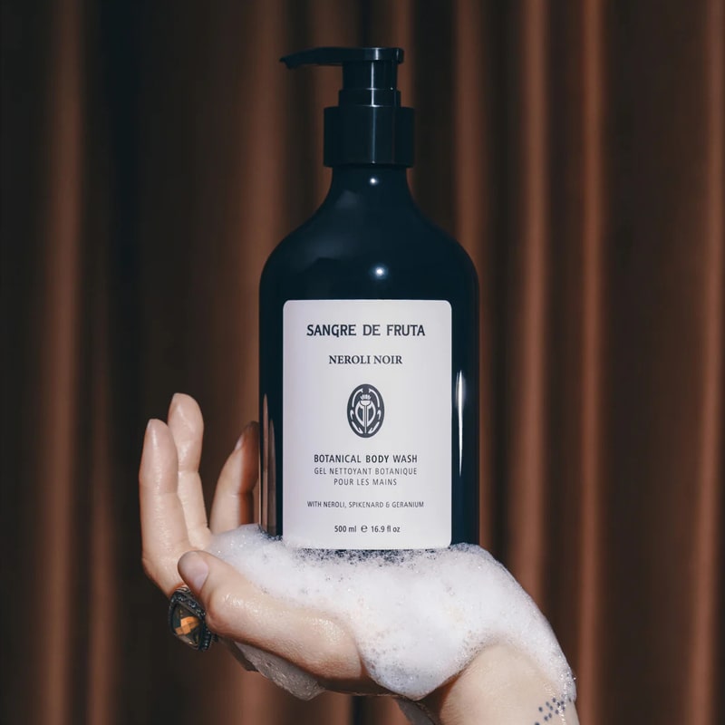 Lifestyle shot of Sangre de Fruta Botanical Body Wash Neroli Noir (500 ml) in hand of model with soap suds in palm