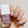 Close up of model wearing Kure Bazaar Nail Lacquer - Flamingo (10 ml) and holding bottle
