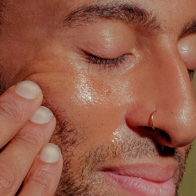 Close up shot of model applying Bathing Culture Outer Being Face &amp; Body Oil to face