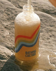 Close up shot of Bathing Culture Refillable Rainbow Glass Mind and Body Wash in Cathedral Grove (16 oz) shown being refilled