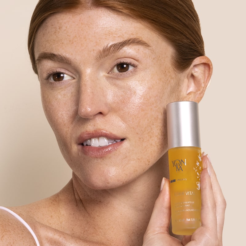 Model holding Yon-Ka Paris Elixir Vital with product on her face