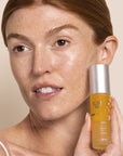 Model holding Yon-Ka Paris Elixir Vital with product on her face