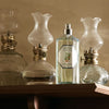 Lifestyle shot of Carriere Freres Orange Blossom Room Spray (200 ml) on wood shelf with vintage lanterns in the background