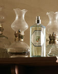 Lifestyle shot of Carriere Freres Orange Blossom Room Spray (200 ml) on wood shelf with vintage lanterns in the background