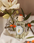 Lifestyle shot of Carriere Freres Orange Blossom Room Spray (200 ml) with flowers in the background