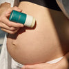 Mother holding Mother Mother Balm (2 oz) against a pregnant belly.
