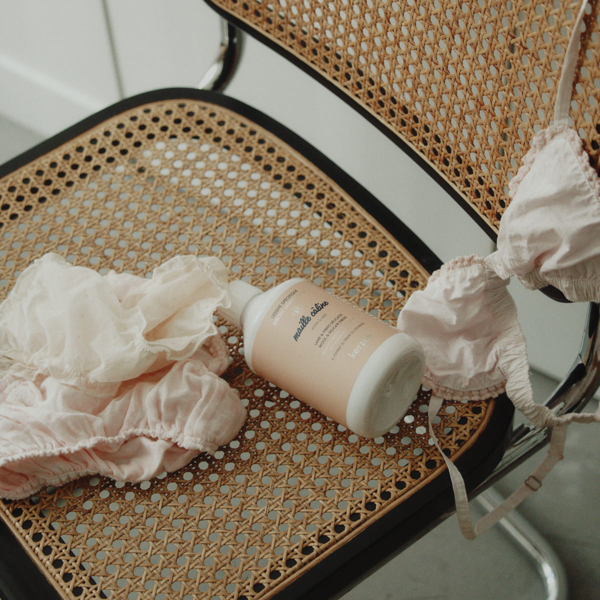 Kerzon Laundry Soap - Maille Caline (500 ml) - product shown on wicker chair with linens. 