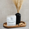 Bathorium Ancient Oat Hydration Crush Bath Soak - packaging on wood tray next to black vase