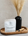 Bathorium Ancient Oat Hydration Crush Bath Soak - packaging on wood tray next to black vase