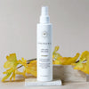 Innersense Organic Beauty Hair Love Prep Spray (6.7 oz) with yellow flowers on a neutral background