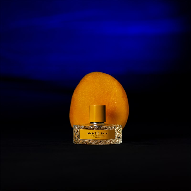 Vilhelm Parfumerie Mango Skin Eau de Parfum - product shown in front of mango on blue background
