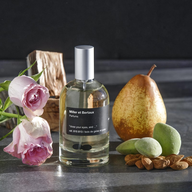 Miller Et Bertaux Close your eyes and... Eau de Parfum (100 ml) lifestyle shot top view, with pink roses, pear, wood and other ingredients in the background