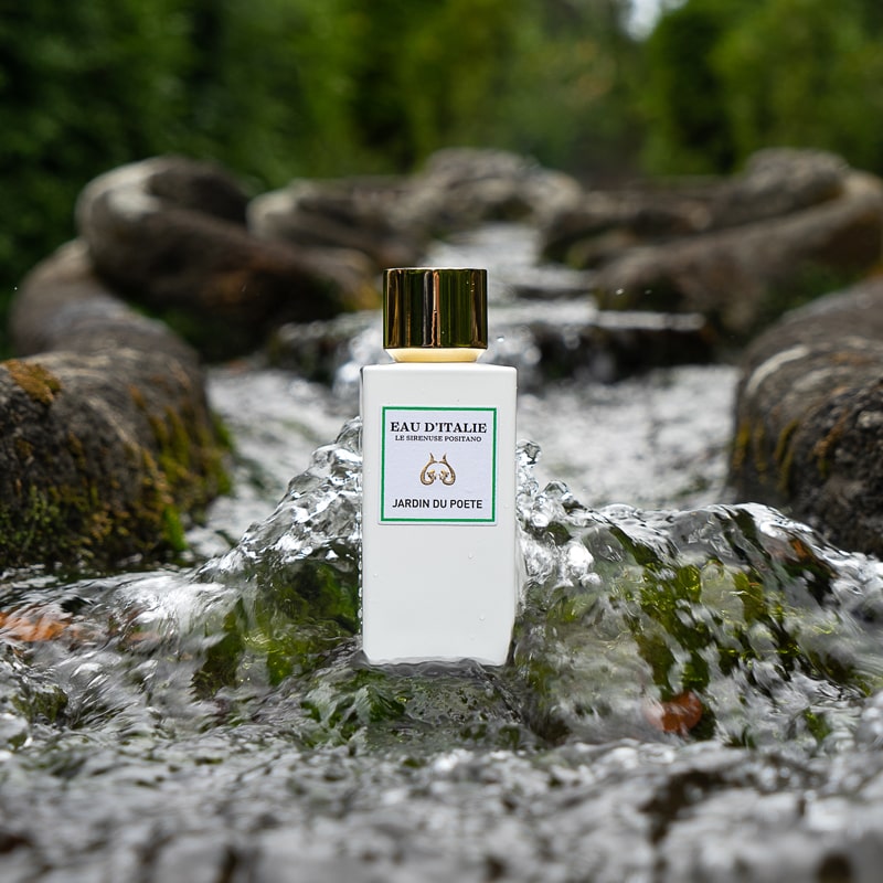 Lifestyle shot of Eau d&#39;Italie Jardin du Poete Eau de Parfum Spray (100 ml) in the middle of stream with water cascading around the sides