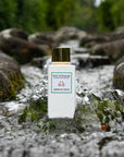Lifestyle shot of Eau d'Italie Jardin du Poete Eau de Parfum Spray (100 ml) in the middle of stream with water cascading around the sides