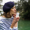 Lifestyle shot of model holding Eau d'Italie Un Bateau Pour Capri Eau de Parfum Spray (100 ml) with lake in the background