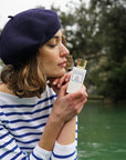 Lifestyle shot of model holding Eau d'Italie Un Bateau Pour Capri Eau de Parfum Spray (100 ml) with lake in the background
