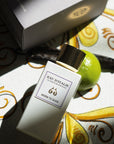 Lifestyle shot top view of Morn to Dusk Eau de Parfum Spray (100 ml) and box with decorative tile, lime and vanilla pod in the background