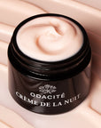 Lifestyle shot of Odacite Creme de la Nuit (50 ml) shown without lid to show cream with cream in the background