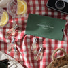 Lifestyle shot top view of Laboratory Perfumes Lifestyle Set with box shown and bottles on top of red checkered tablecloth