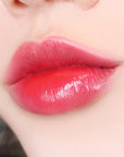 Paul + Joe Liquid Rouge Shine (0.28 oz, Plum Puree (02)) shown on model's lips