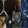 Diptyque Orpheon Eau de Parfum (75 ml)  - product shown on glass counter with plants and glassware. 