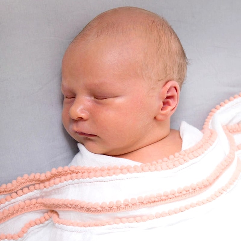 Newborn shown with Malabar Baby Luxe Silky Soft Bamboo Cotton Swaddle - Peach Pom Pom Trim (1 pc)