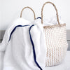 Lifestyle shot of Malabar Baby Luxe Silky Soft Bamboo Cotton Swaddle – Navy Pom Pom Trim (1 pc) shown in wicker handbag
