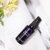 de Mamiel First Fix Stress Response Serum beauty shot pictured on a book with a flower nearby