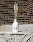 Lifestyle shot of Eau d’Italie Signature Scent Diffuser (240 ml) on top of ornate column with bricks in the background 