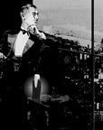 Illustration of gentleman wearing tuxedo and looking out from high rise building with cityscape below and Lubin Upper Ten Eau de Parfum bottle sitting on small table next to him