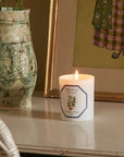 Lifestyle shot of Carriere Freres Orange Blossom Candle showing lit candle next to vase and framed art in the background