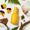 Ursa Major Mountain Glow Golden Serum (1 oz) - product shown surrounded by flowers and wood