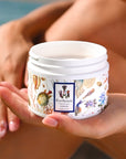 Model holding jar of Carthusia A’mmare Body Lotion (250 ml) with lid off in palm of her hand