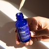 Close up of model holding Lifestyle shot of Odacite Vitamin C & E + Hyaluronic Acid Brightening Serum bottle with dropper